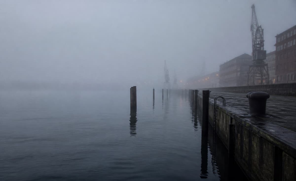 Nebliges Hafenwasser mit dunklen Konturen